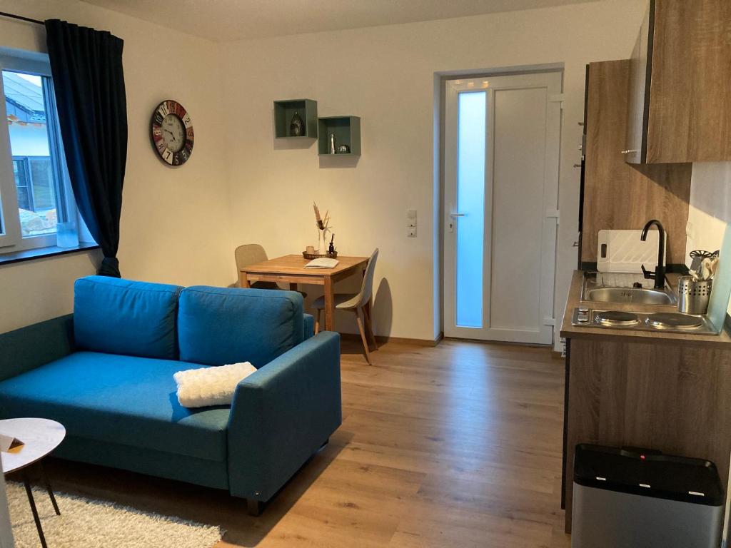 a living room with a blue couch and a table at Ferienwohnung Am Hochkelberg in Bereborn