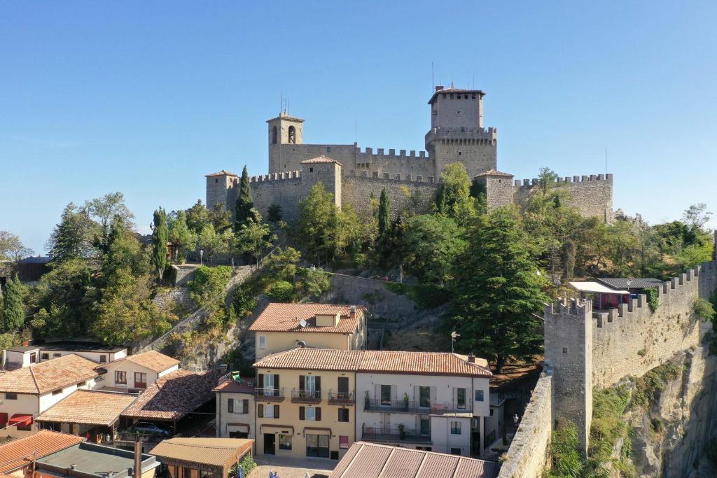 een kasteel bovenop een heuvel met huizen bij Hotel Rosa in San Marino