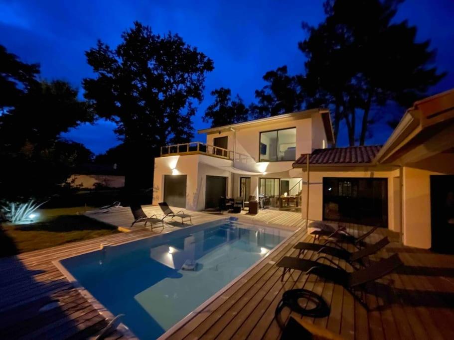 a house with a swimming pool at night at Villa confort piscine chauffée*/10KM CONTIS Plage in Lit-et-Mixe