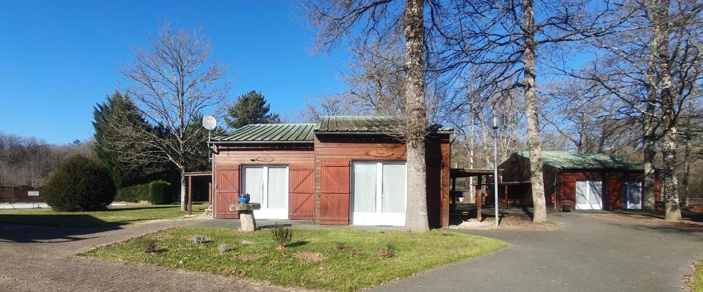 Cabaña de madera pequeña con puertas blancas en un parque en Chalets Moulière Evasion, en Montamisé