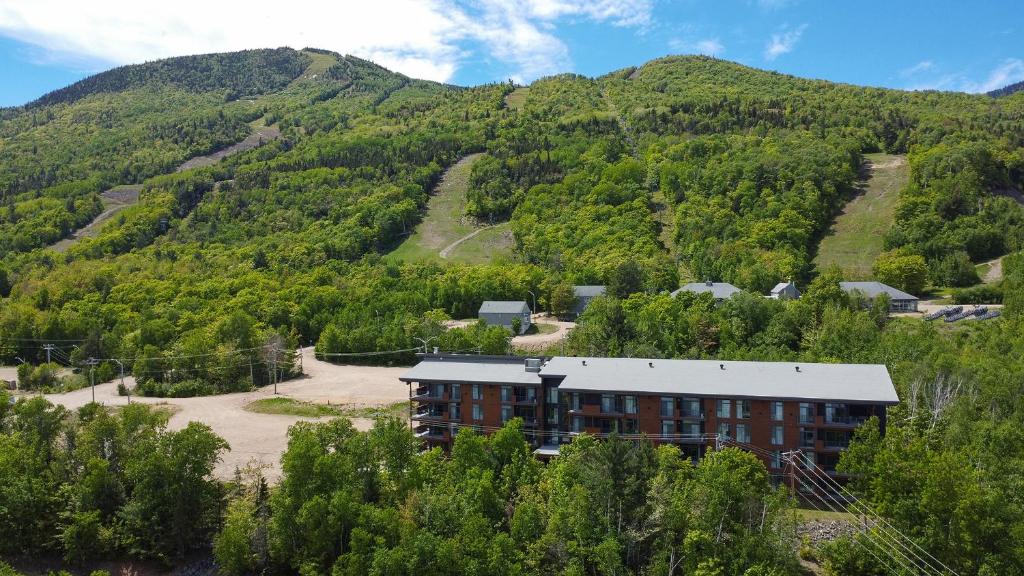 a building in the middle of a mountain at Les Appartements du Massif de Charlevoix in Petite-Rivière-Saint-François