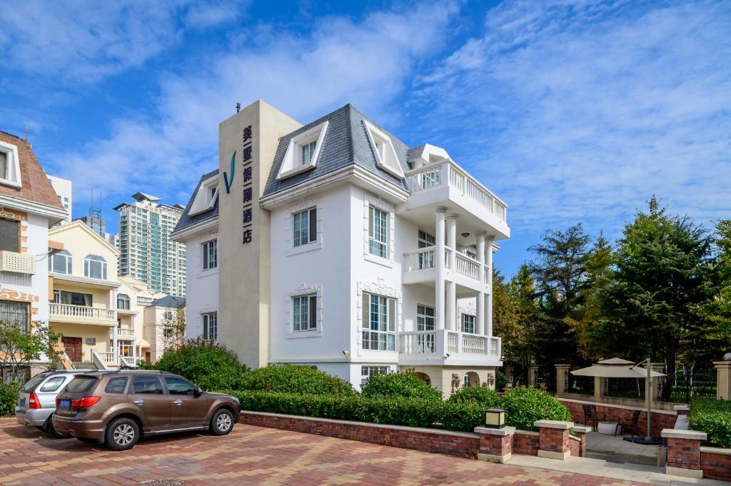 a white house with a car parked in front of it at Qingdao Villa Inn No.12 Seaside (Wusi Suqare) in Qingdao
