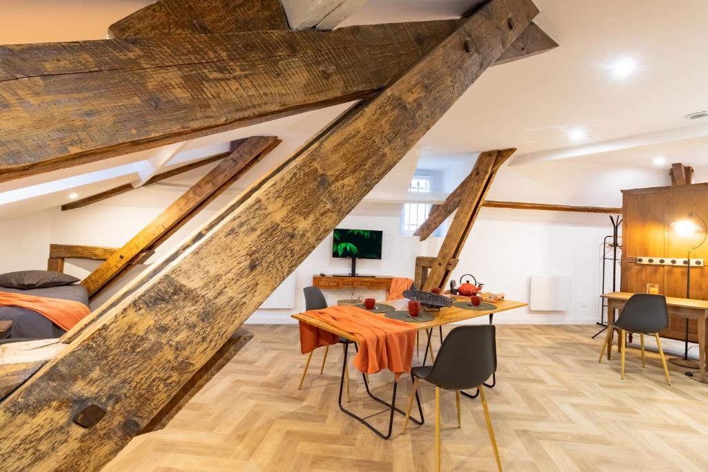 Cette chambre est dotée de poutres apparentes, d'une table et de chaises. dans l'établissement D'am Chic Nomade Campagne en ville, à Périgueux