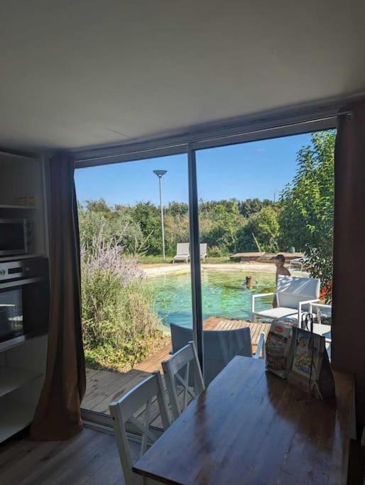 - une salle à manger avec une table et une vue sur la piscine dans l'établissement Chalet climatisé en campagne avec baignade privée, à Lagnes