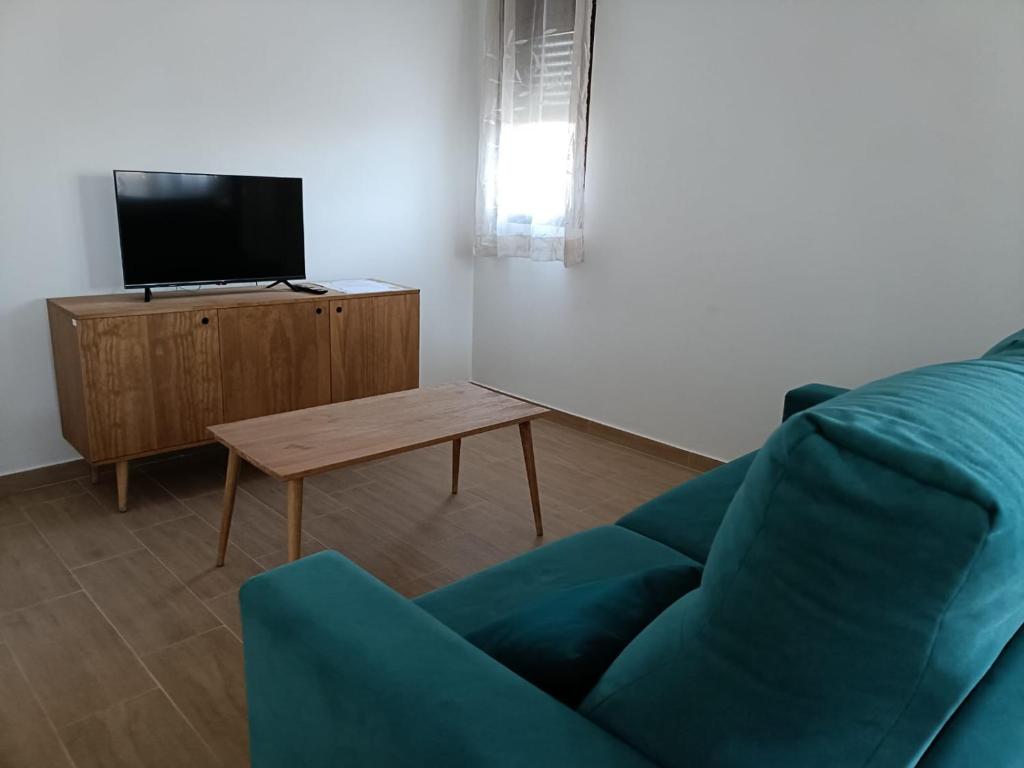 uma sala de estar com um sofá azul e uma mesa em Apartamentos Rurales Fuente del Peral em Alobras