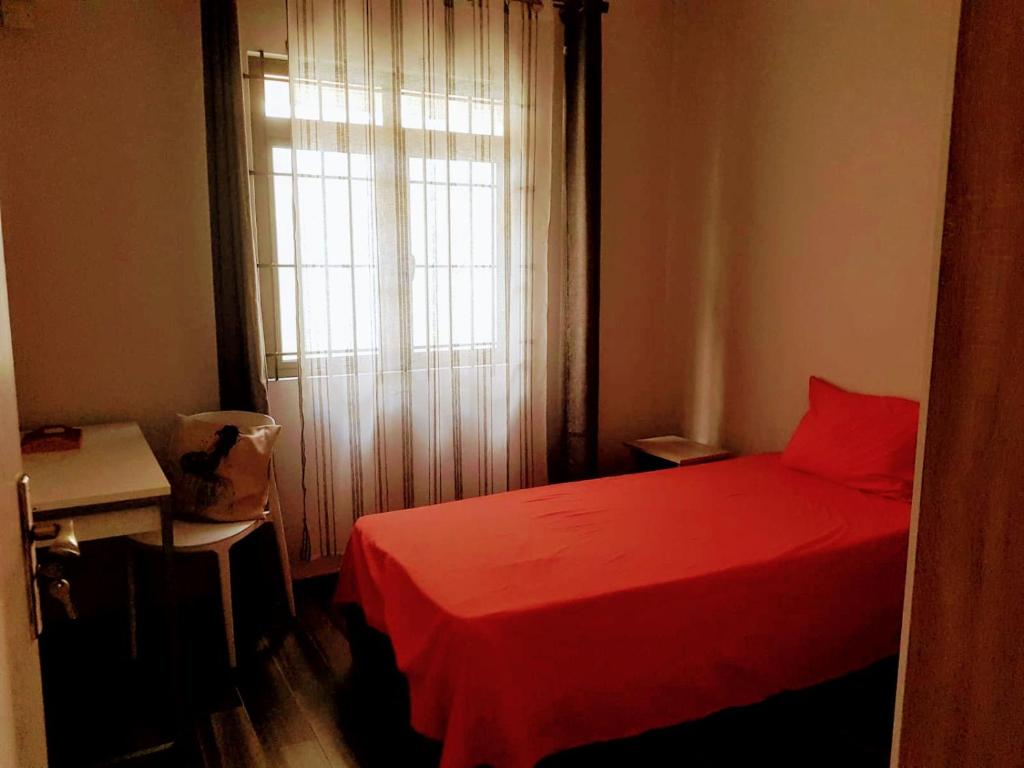 un letto rosso in una piccola stanza con finestra di Cosy 3 bedroom apartment a Flic-en-Flac