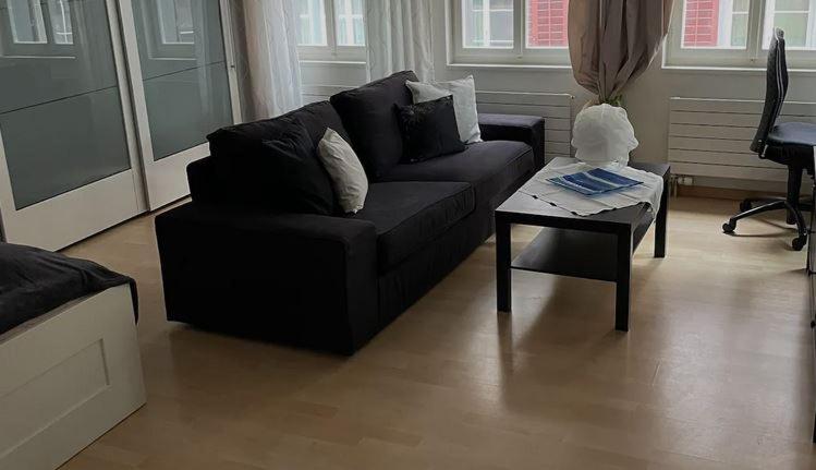 ein Wohnzimmer mit einem schwarzen Sofa und einem Couchtisch in der Unterkunft 1.5 Zimmer Wohnung Altstadt Zug in Zug