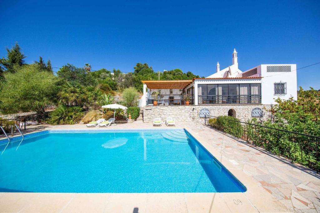 une villa avec une piscine en face d'une maison dans l'établissement Villa Jacaranda Bordeira, à Corotelo
