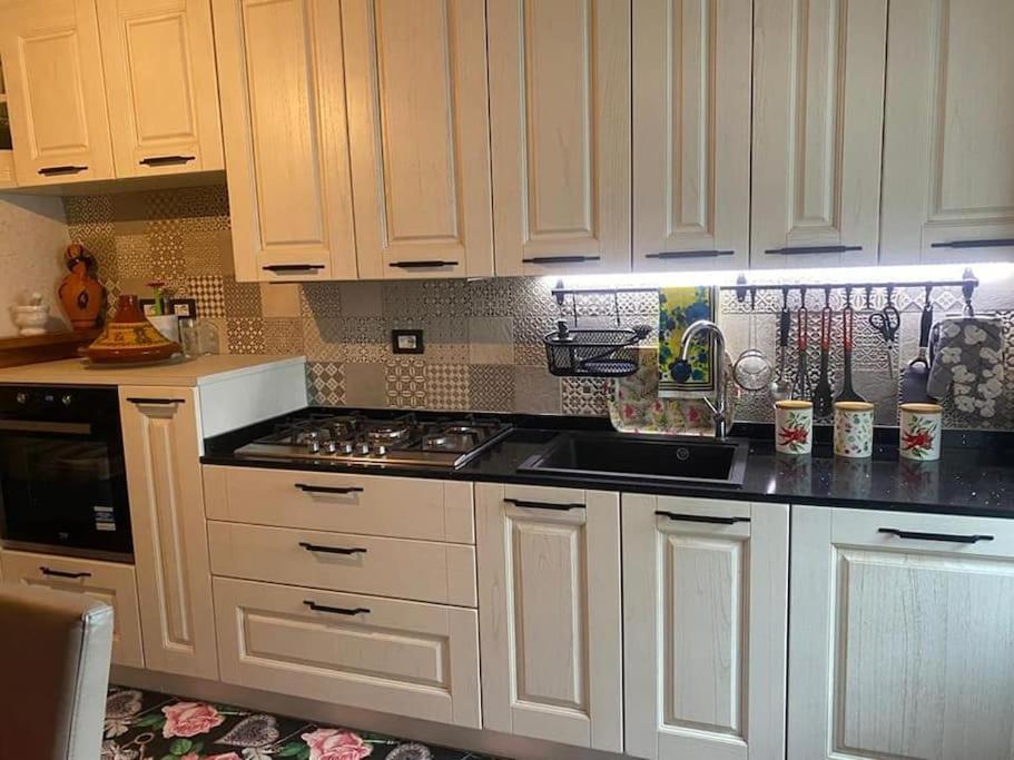 Una cocina con gabinetes blancos y un horno de estufa. en Grazioso appartamento, en Pieve Santo Stefano