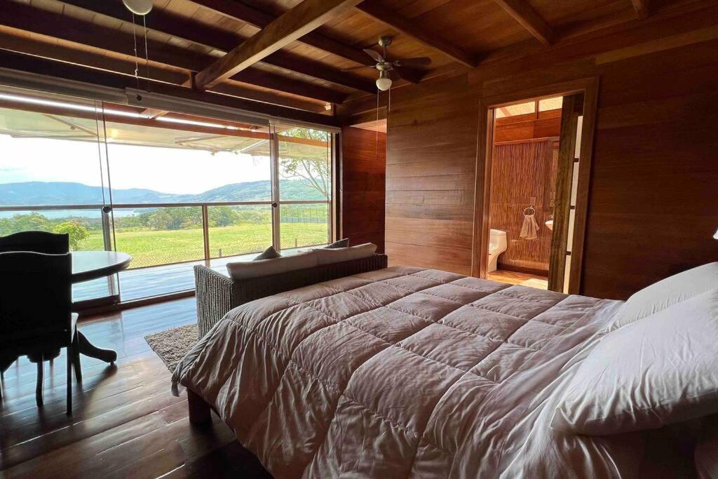 a bedroom with a large bed and a large window at Vista panorámica de Laguna Azul en Sauce-San Martín in Sauce