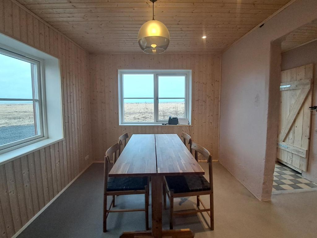 a dining room with a wooden table and two windows at The Forgotten Farmhouse in Skogar
