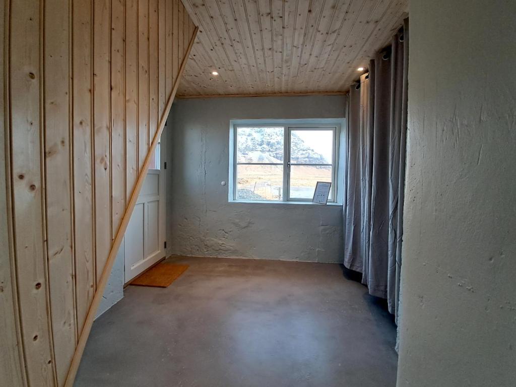 an empty room with a window and a staircase at The Forgotten Farmhouse in Skogar