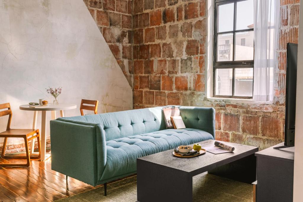a living room with a blue couch and a brick wall at Sonder The Schaeffer in New Orleans