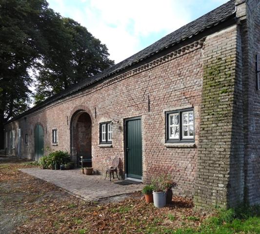 a brick building with a green door and a patio at B&B Boerderij La Trappe Deurne in Deurne