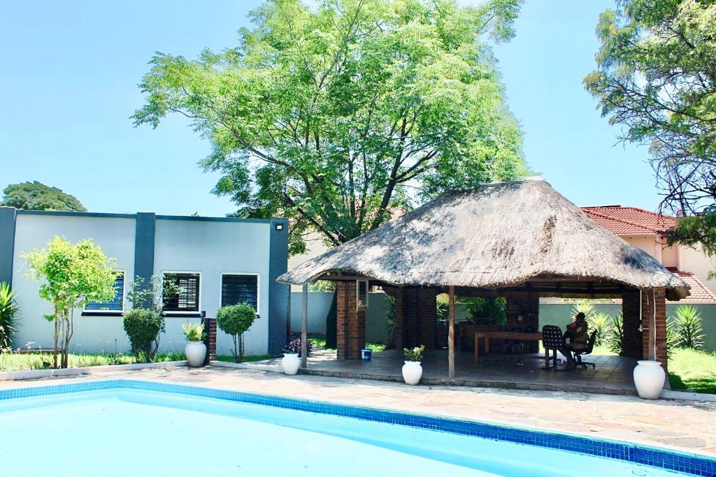 a hut next to a swimming pool next to a house at Exquisite 1-Bed Apartment in Sandton in Johannesburg
