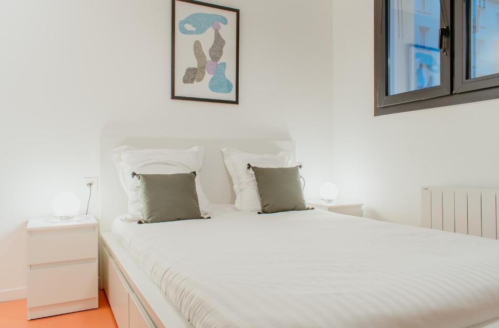 - un lit blanc avec des draps et des oreillers blancs dans l'établissement Paillette, au Havre