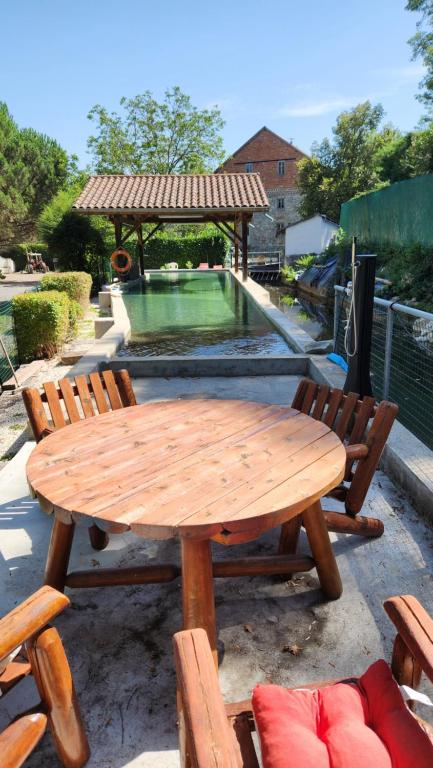 a wooden picnic table with chairs and a swimming pool at Détendez-vous à Montverdun in Montverdun