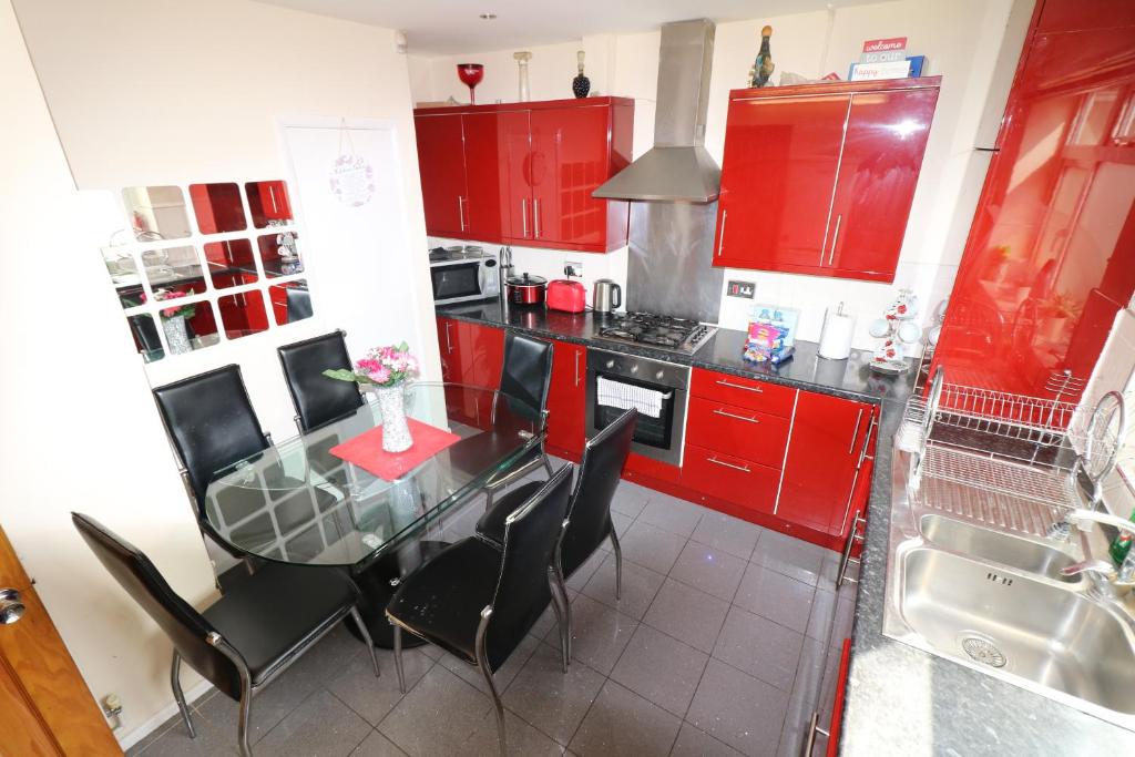a kitchen with red cabinets and a glass table with chairs at 3 Bedroom House-Garden-Stratford-Olympic Park in London