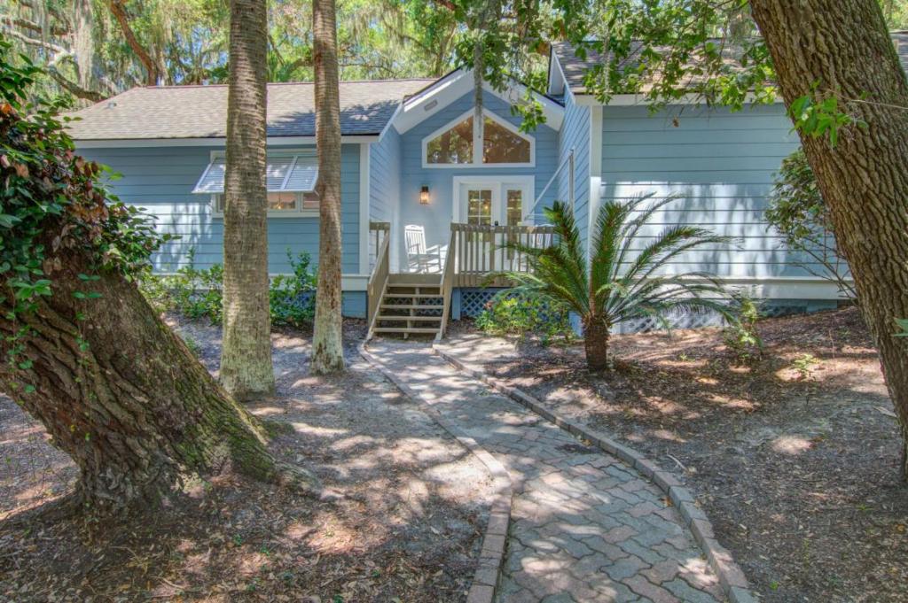 una casa azul con árboles delante de ella en 2650 High Hammock Rd, en Seabrook Island