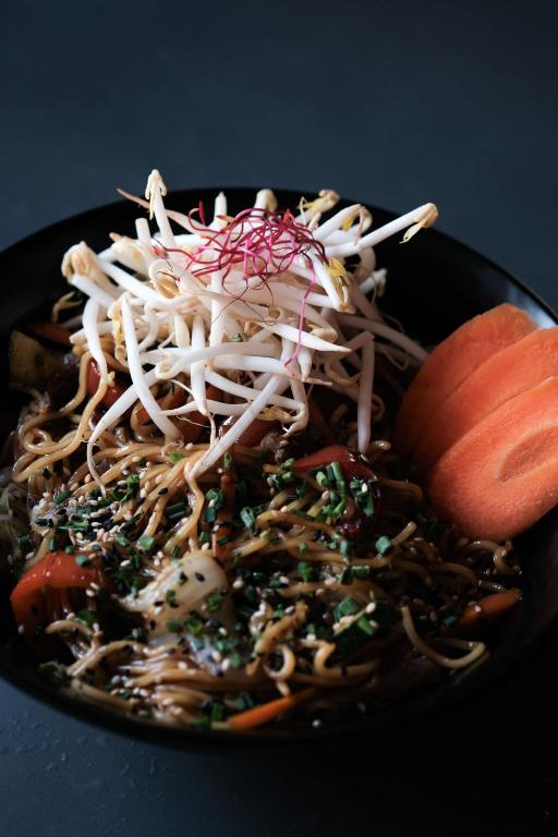 a black plate of food with noodles and vegetables at Prinsotel La Dorada & Spa in Playa de Muro