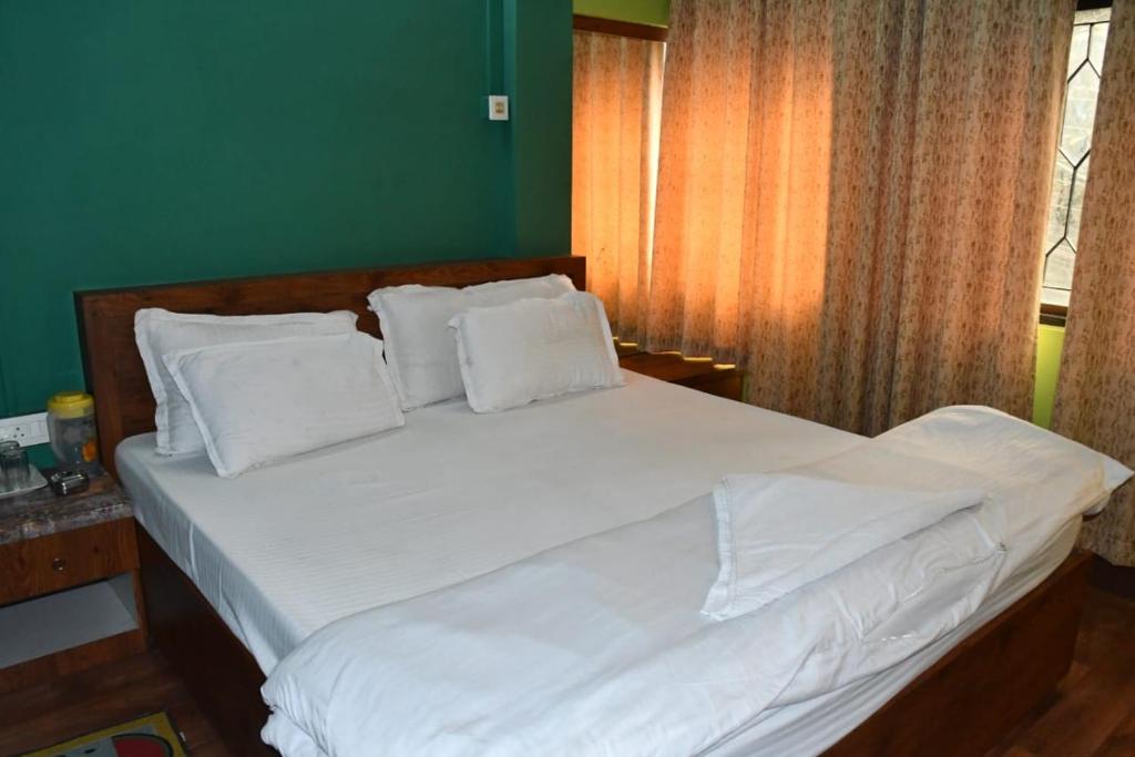 sypialnia z dużym łóżkiem z białą pościelą i poduszkami w obiekcie Kajal's Home stay w mieście Siliguri