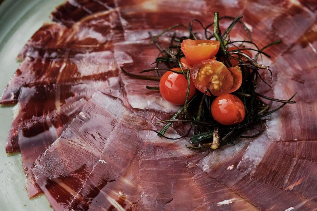 a plate of meat with tomatoes on top of it at Prinsotel La Dorada & Spa in Playa de Muro
