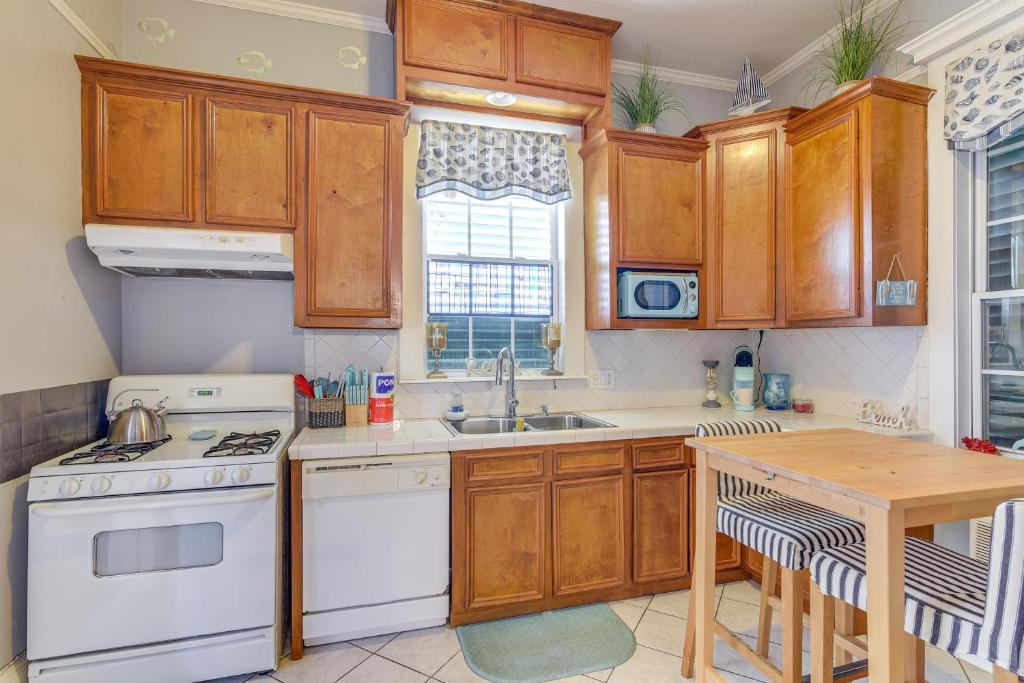 a kitchen with white appliances and wooden cabinets at Coastal Galveston Studio about 1 Mi to Beach! in Galveston