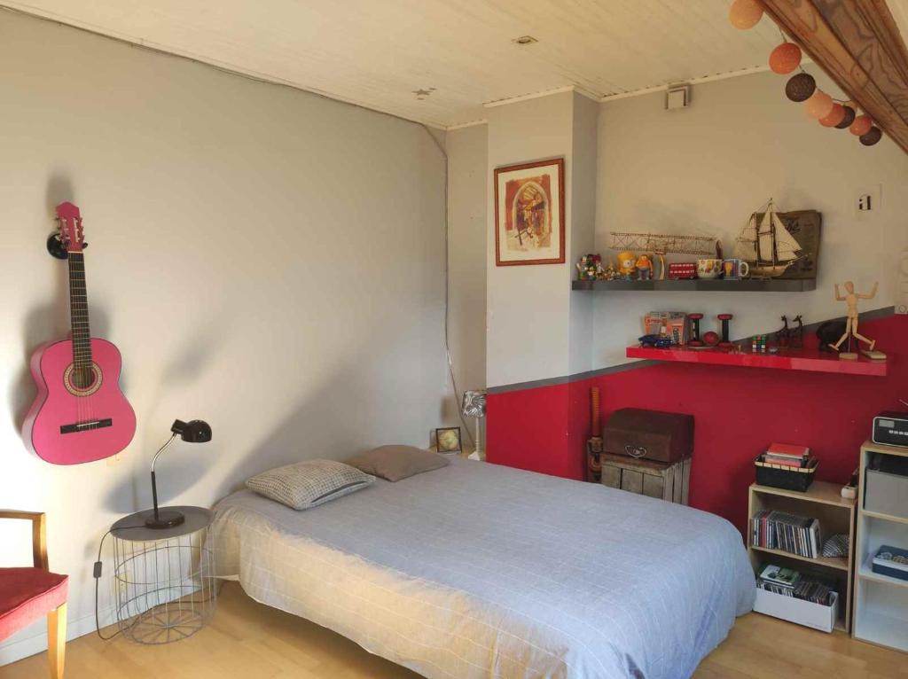 Un dormitorio con una cama y una guitarra en la pared en Chambre proche paris JO 2024, en Chaumontel