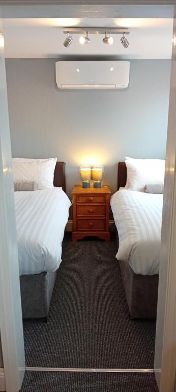 sypialnia z 2 łóżkami pojedynczymi i stolikiem nocnym między nimi w obiekcie Home and Away Guesthouse w mieście Bridlington
