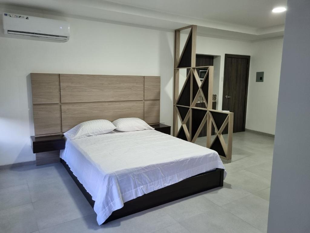 a bedroom with a large bed with a wooden headboard at SUITES GARZOTA in Guayaquil