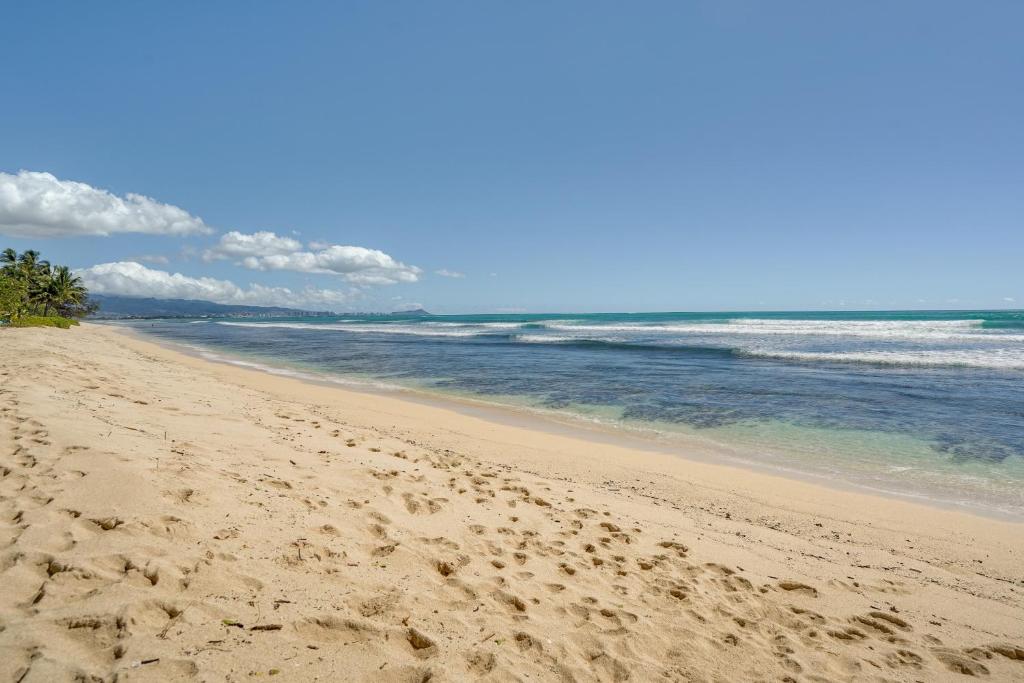 a beach with footprints in the sand and the ocean at Ewa Beach Apartment about 1 Mi to Puʻuloa Beach Park! in Kapolei