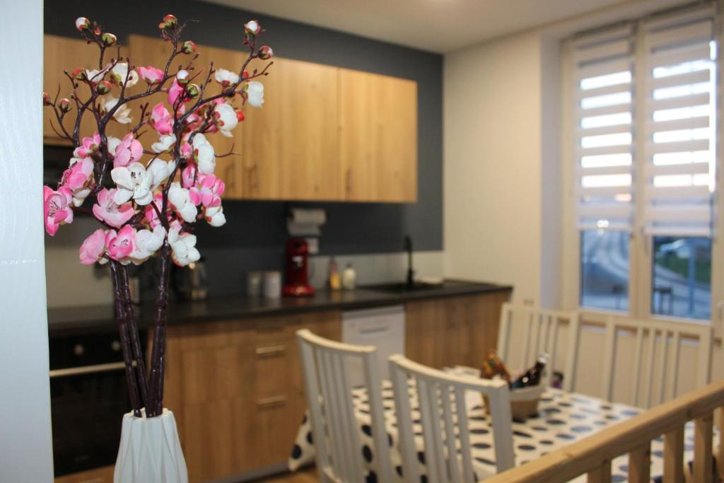 une cuisine avec une table et un vase avec des fleurs roses dans l'établissement Appartement Royale, à Rocroi
