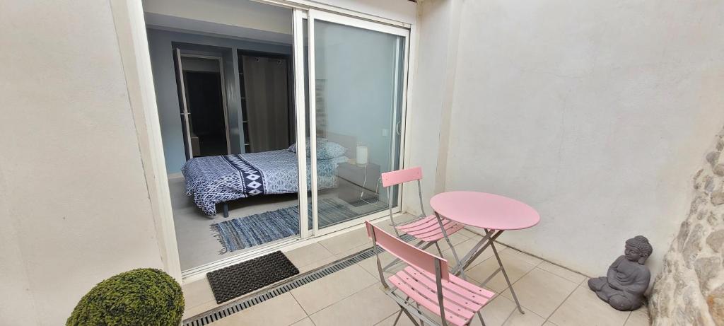 a small balcony with a pink table and chairs at Appartement 2 CHAMBRES meuble a saix 48 m2 avec COUR in Saix
