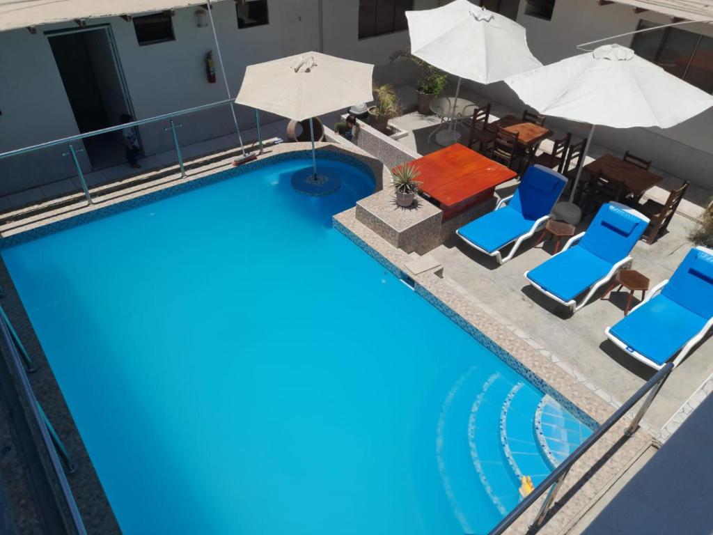 an overhead view of a pool with chairs and umbrellas at HOTEL PARAACO in Paracas