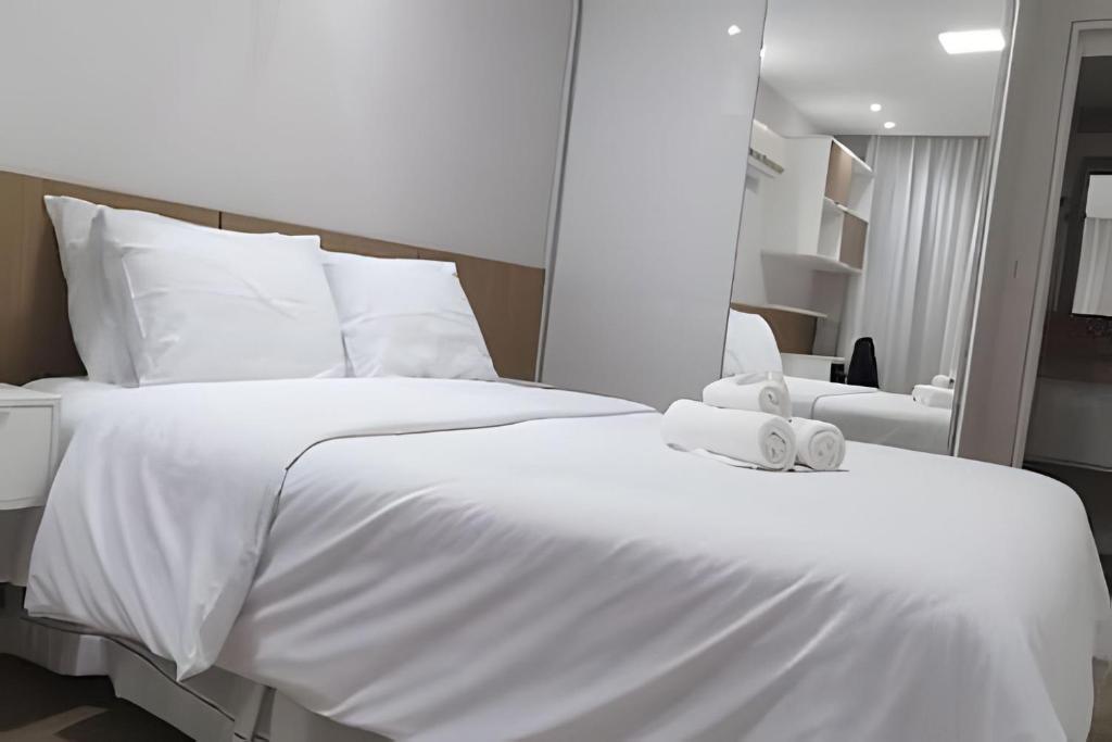 - un lit blanc avec des draps et des oreillers blancs dans l'établissement Flat em Tambaú 50m da praia, à João Pessoa