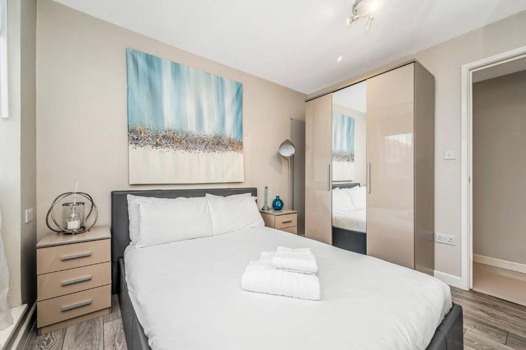 um quarto com uma grande cama branca e um espelho em Pass the Keys Whitechapel Central Apartment em Londres