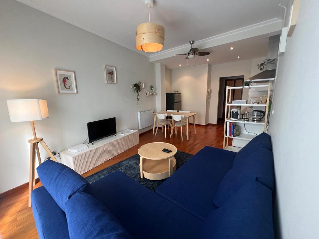 uma sala de estar com um sofá azul e uma mesa em A estrenar ,con vistas al mar y aparcamiento gratis en el casco Viejo-Centro-Zona portuaria em Vigo