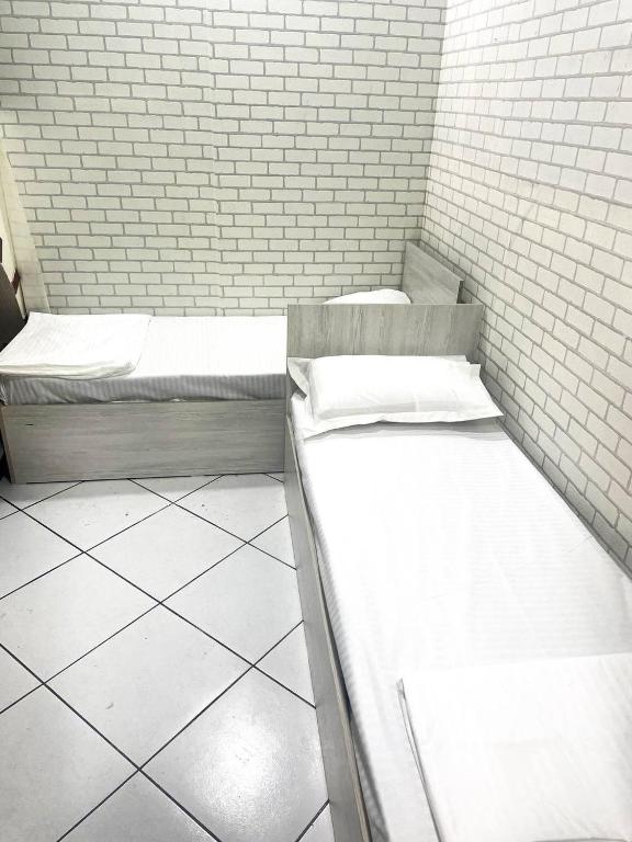a room with two beds and a brick wall at Shinam Hostel in Chilanzar