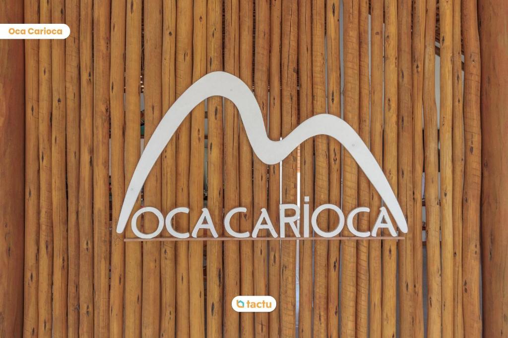 ein Schild an der Seite eines Holzzauns in der Unterkunft Oca Carioca no Pontal do Maceió por Tactu 