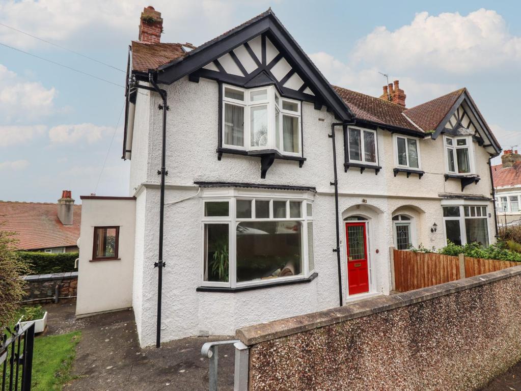 una casa bianca con una porta rossa di Highgate a Llandudno
