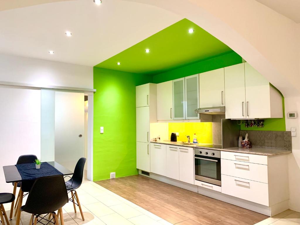 eine Küche mit grünen Wänden sowie einem Tisch und Stühlen in der Unterkunft Centrally located Apartment Vienna included Netflix in Wien