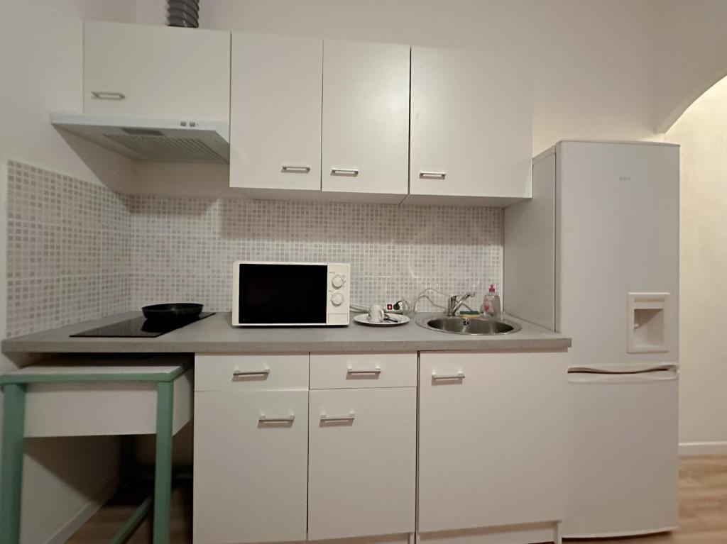 a white kitchen with a sink and a microwave at Charmant Studio avec Balcon in Perpignan
