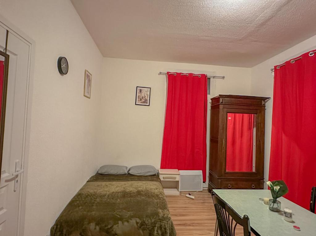 a bedroom with red curtains and a bed and a table at Charmant Studio avec Balcon in Perpignan