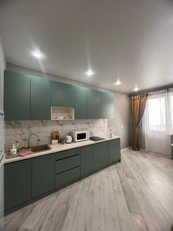 een keuken met groene kasten en een aanrecht bij Nureke Apartment's in Alma-Ata