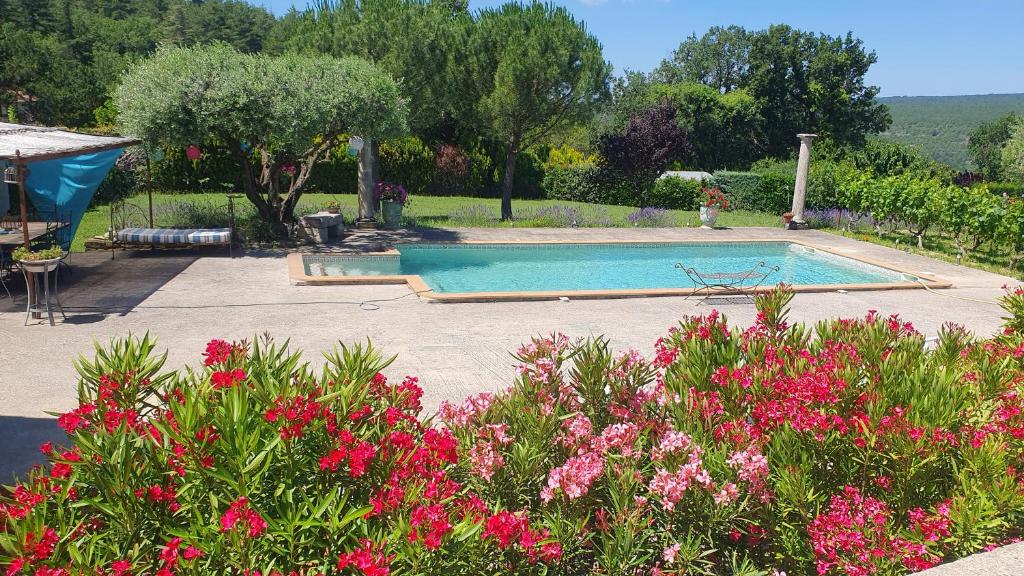 einen Pool in einem Garten mit rosa Blumen in der Unterkunft la chambrette in Lincel