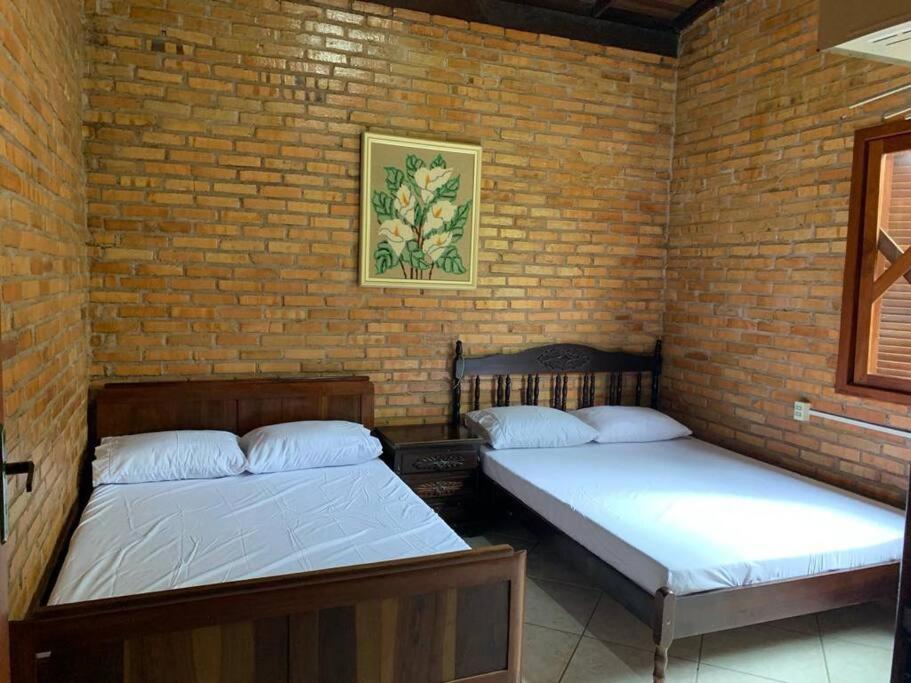 2 camas en una habitación con una pared de ladrillo en Sítio com piscina incrível, en Santo Amaro da Imperatriz