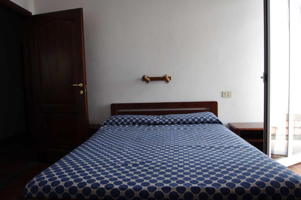 a bedroom with a bed with a blue comforter at AGRITURISMO LA FATTORIA in Ranzo-Borgo