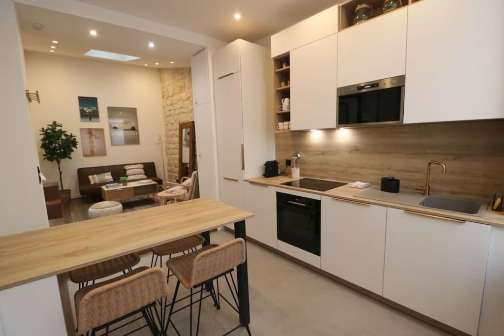 Cosy 2 chambres / Père-Lachaise في باريس: مطبخ مع طاولة وكراسي وغرفة معيشة