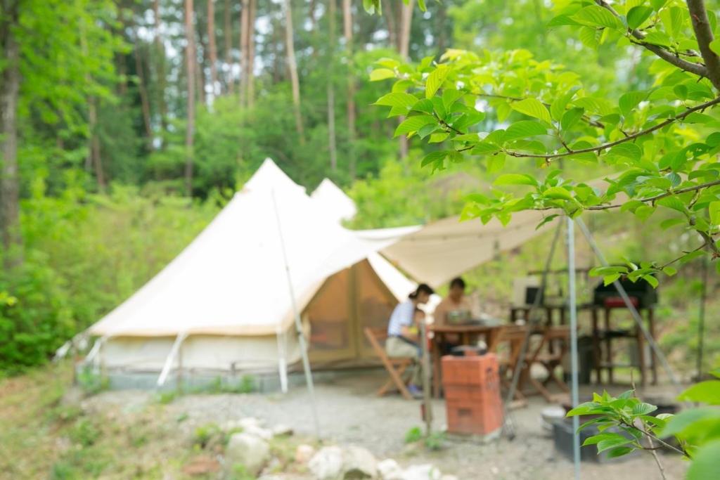 two people sitting at a table in front of a tent at Hakushu/Ojiro FLORA Campsite in the Natural Garden - Vacation STAY 11899v in Hokuto