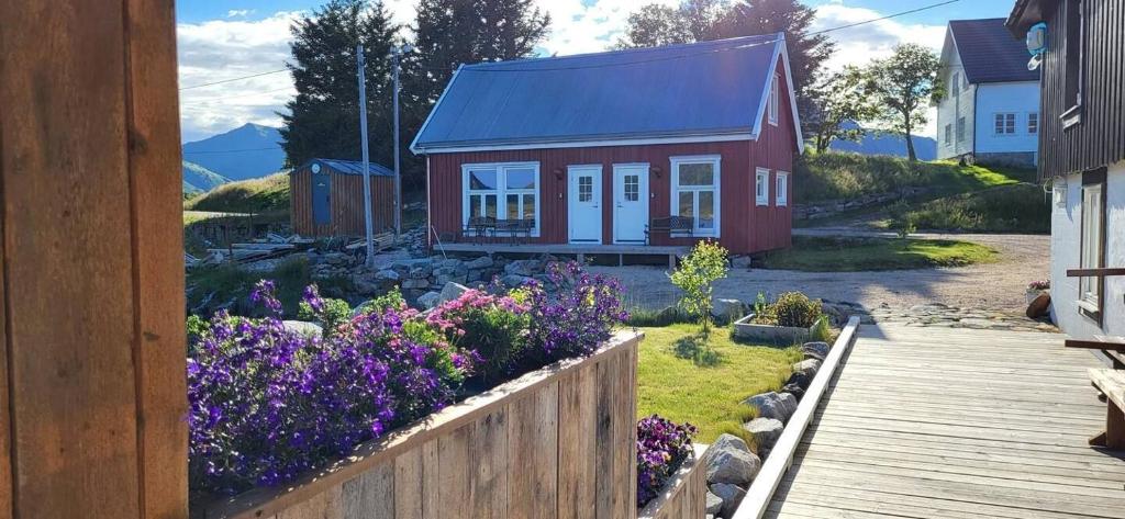 a small red house with flowers in front of a yard at Cabin Borgvåg Small in Straum